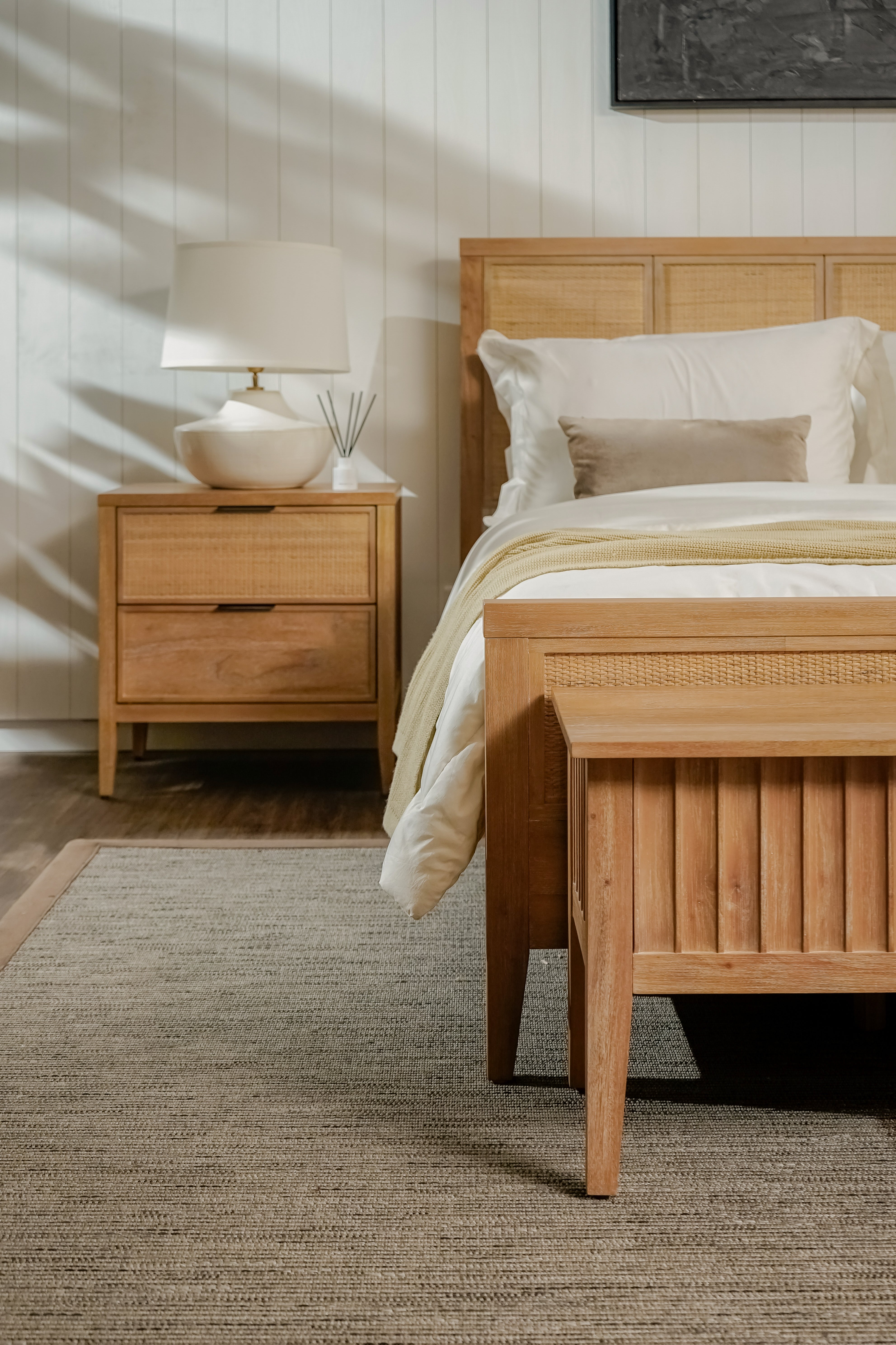 Wooden bed and nightstand in a bedroom setting with a lamp on the nightstand.