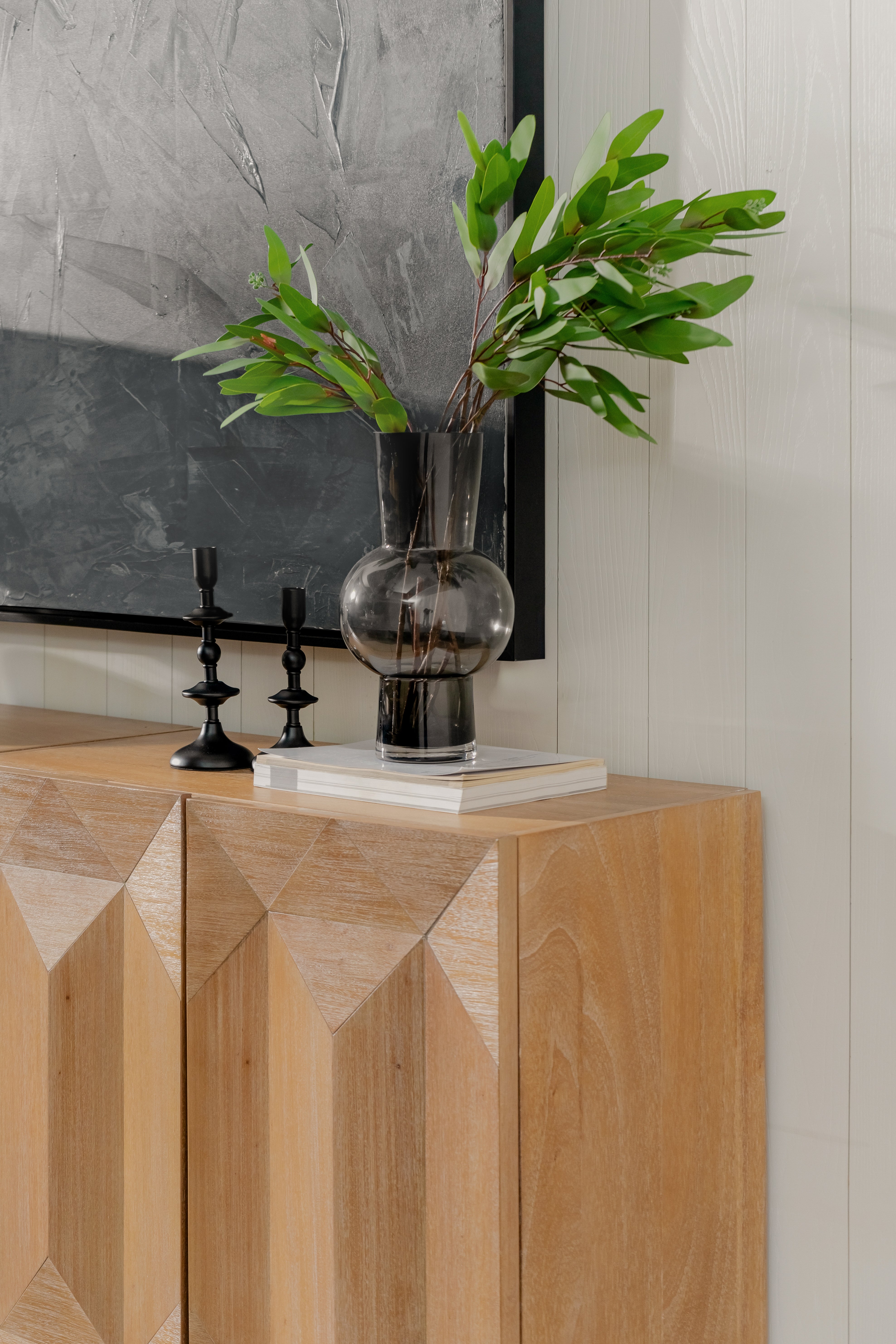 Decorative setup with a vase and plant on a Natural Averi Modular Cabinet against a tiled wall.