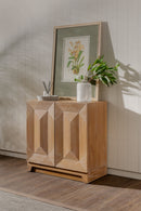 Natural Averi Modular Cabinet with geometric design against a neutral wall with a framed picture and plant.