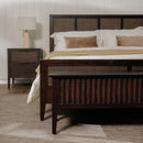 Wooden bed with brown headboard and matching Black Kalana - 2-Drawer Rattan Nightstand in a bedroom setting.