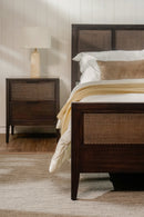 Bedroom with wooden bed and nightstand against a neutral wall.