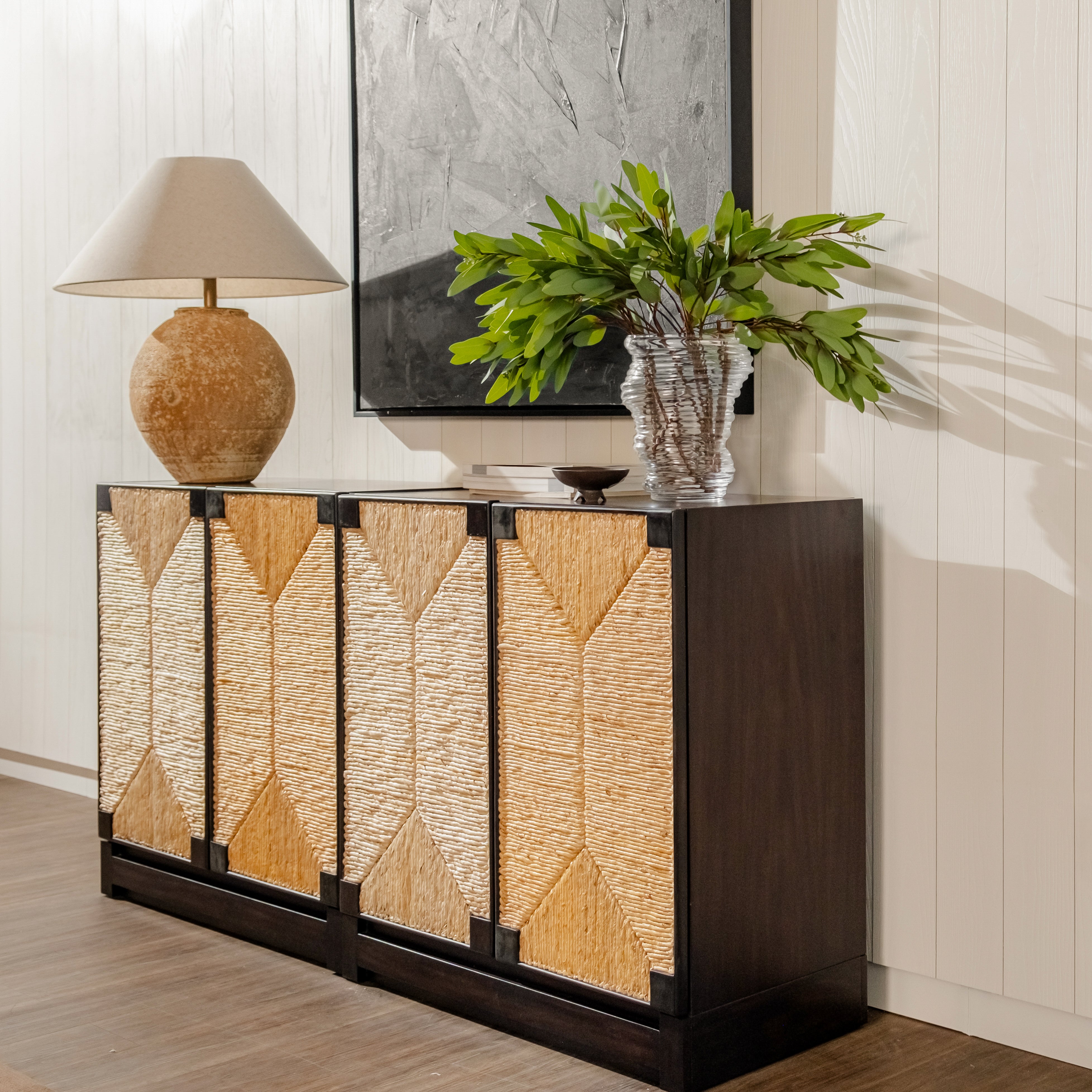 Decorative sideboard with wicker doors, lamp, and plant in a room setting.