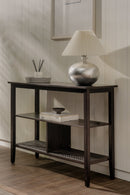 Dark wooden console table with a lamp and decorative items against a neutral wall.