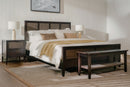 Bedroom with wooden bed, nightstands, and bench in a well-lit room.