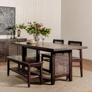 Dining room with a wooden table, chairs, and a bench, featuring a vase of flowers.