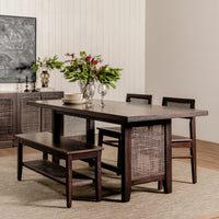 Dining room with a wooden table, chairs, and a bench, featuring a vase of flowers.