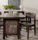 Dining room with a dark wooden table and chairs, featuring a plant and wine glasses.