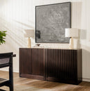 Wooden sideboard with two lamps and a painting in a room with wooden flooring.