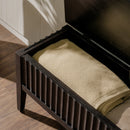 Black metal bench with a folded beige blanket on a wooden floor