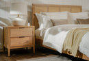 Bedroom with wooden bed and Natural Kalana 2 Drawer Rattan Nightstand, featuring white bedding and a lamp.