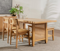 Wooden dining table with chairs and a plant in a room.