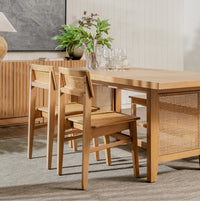 Wooden dining table with chairs in a room with a plant and decorative items.