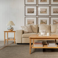 Living room with beige sofa, wooden coffee table, and framed pictures on the wall.