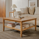 Wooden coffee table with books and a lamp in a living room setting