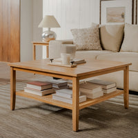 Wooden coffee table with books and a lamp in a living room setting