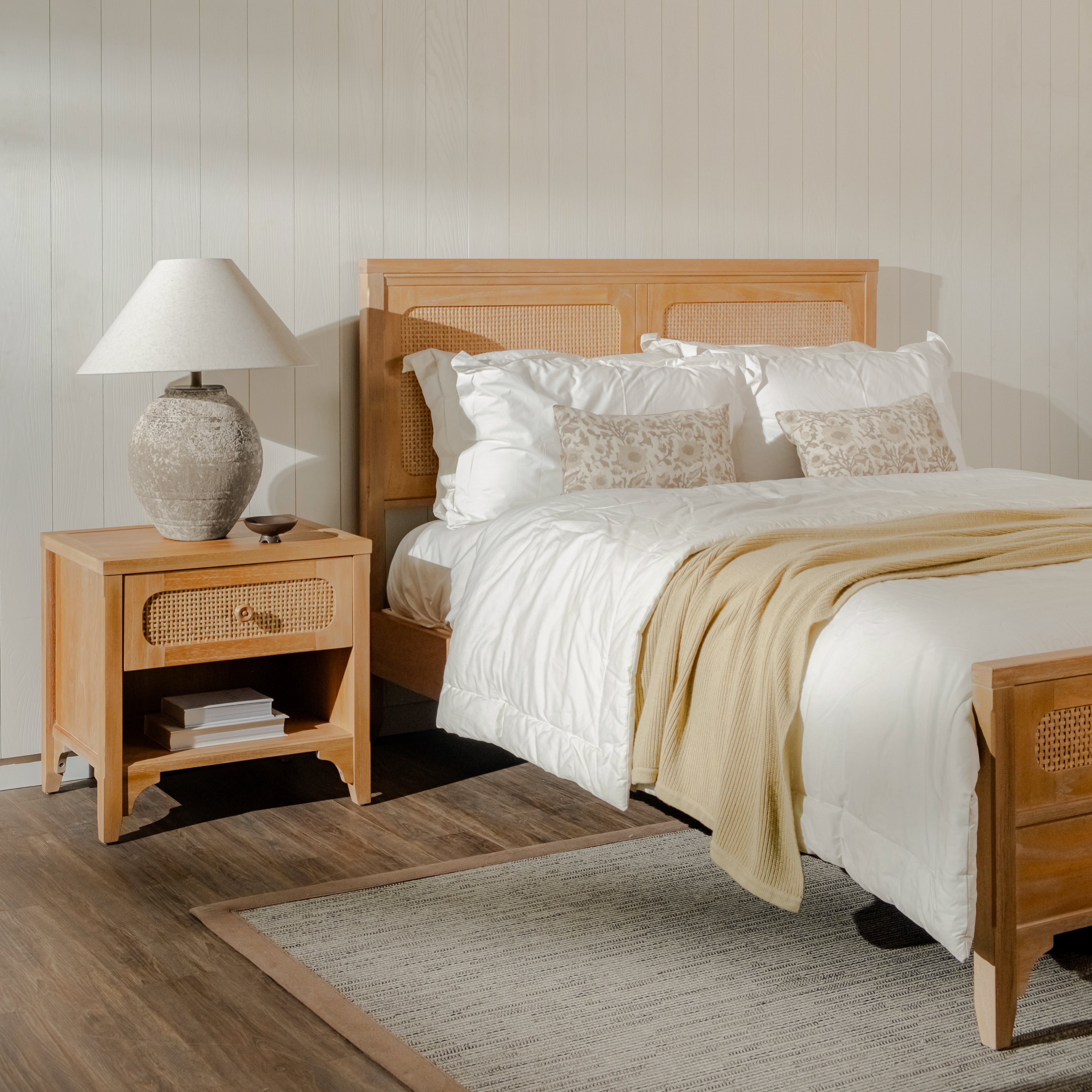 Bedroom with wooden bed and nightstand, white bedding, and decorative pillows.