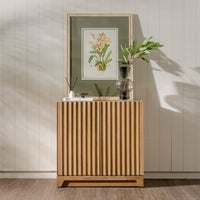 Wooden sideboard with decorative items against a light wooden paneled wall.