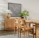 Dining room with wooden table, chairs, and a lamp in a well-lit room.