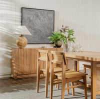 Dining room with wooden table, chairs, and a lamp in a well-lit room.
