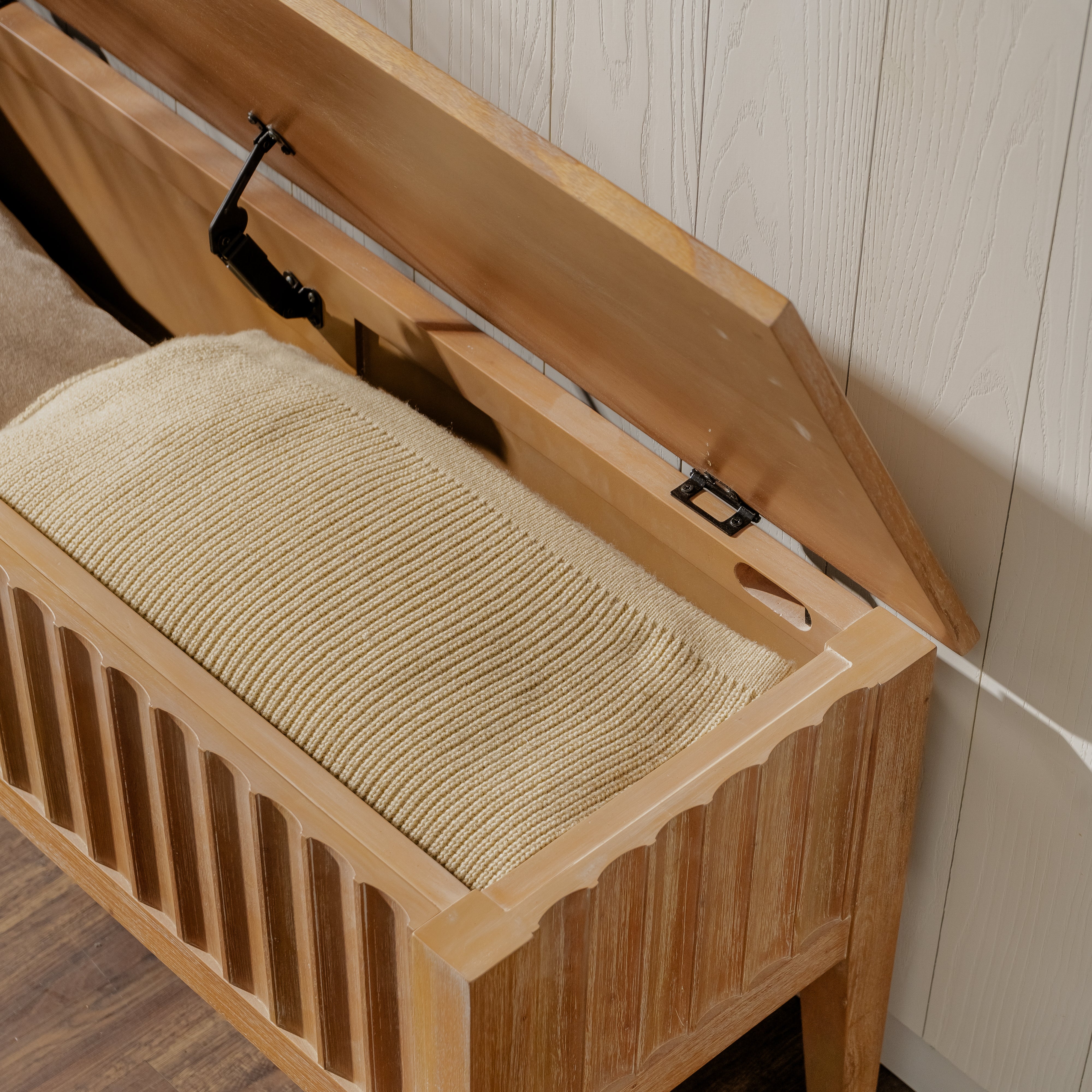Wooden bench with a textured cushion on a wooden floor.