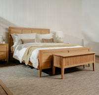 Wooden bed with matching nightstands and bench in a bedroom setting.